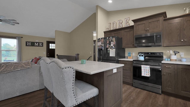 kitchen featuring dark hardwood / wood-style flooring, lofted ceiling, a breakfast bar, dark brown cabinets, and appliances with stainless steel finishes