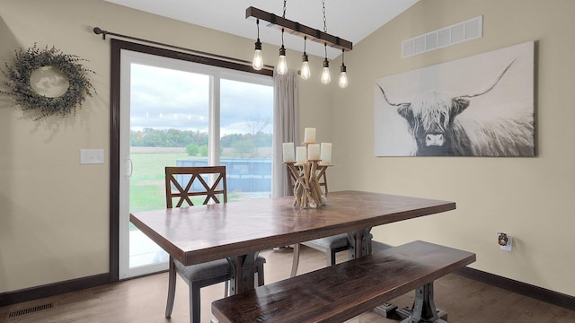 dining area featuring hardwood / wood-style flooring and vaulted ceiling