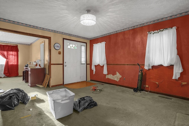 entrance foyer featuring a textured ceiling, light colored carpet, and an inviting chandelier