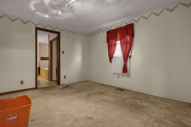 carpeted spare room with rail lighting and a textured ceiling