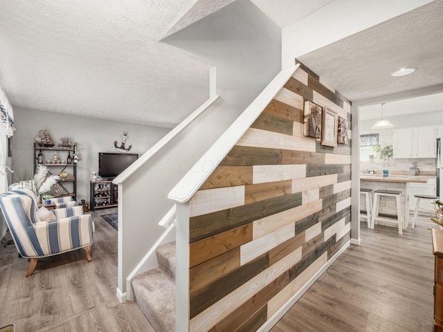 stairway featuring wood-type flooring and a textured ceiling