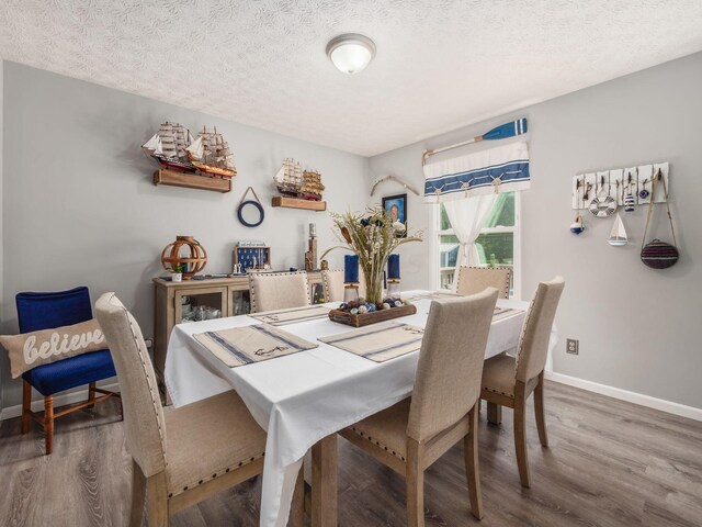 dining space with hardwood / wood-style floors and a textured ceiling