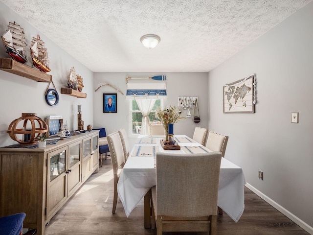 dining space with a textured ceiling and light wood-type flooring