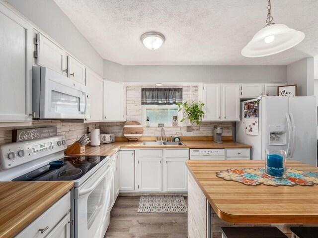 kitchen with white cabinetry, sink, dark wood-type flooring, decorative light fixtures, and white appliances