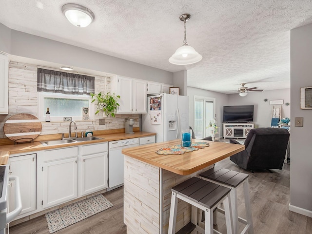 kitchen with white cabinetry, sink, butcher block countertops, pendant lighting, and white appliances