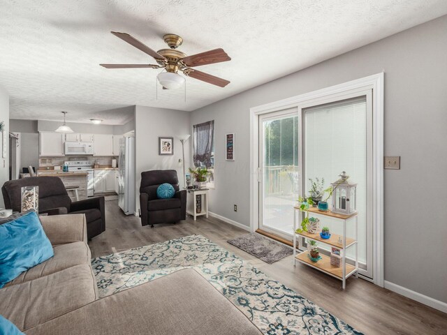 living room with a textured ceiling, ceiling fan, and dark wood-type flooring