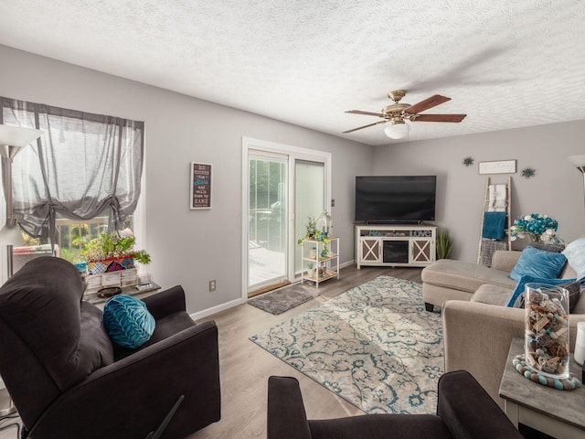 living room featuring ceiling fan, light wood-type flooring, and a textured ceiling