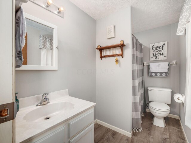 bathroom featuring vanity, a textured ceiling, hardwood / wood-style flooring, and toilet