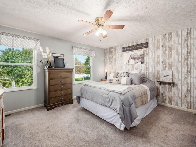 carpeted bedroom with ceiling fan and a textured ceiling