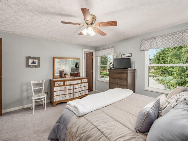 carpeted bedroom with ceiling fan and a textured ceiling