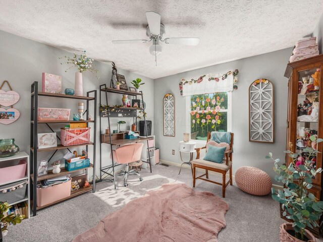 carpeted home office with a textured ceiling and ceiling fan