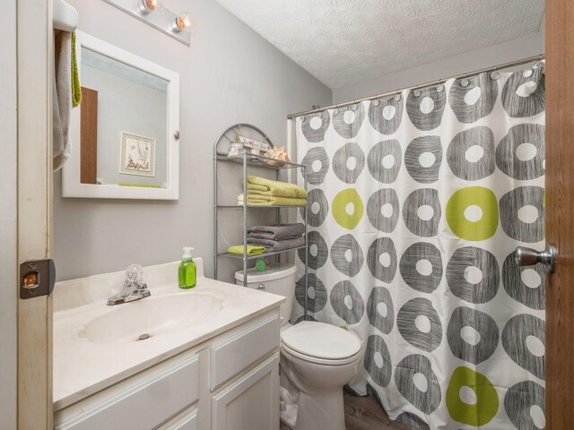 bathroom with vanity, a textured ceiling, hardwood / wood-style flooring, toilet, and curtained shower