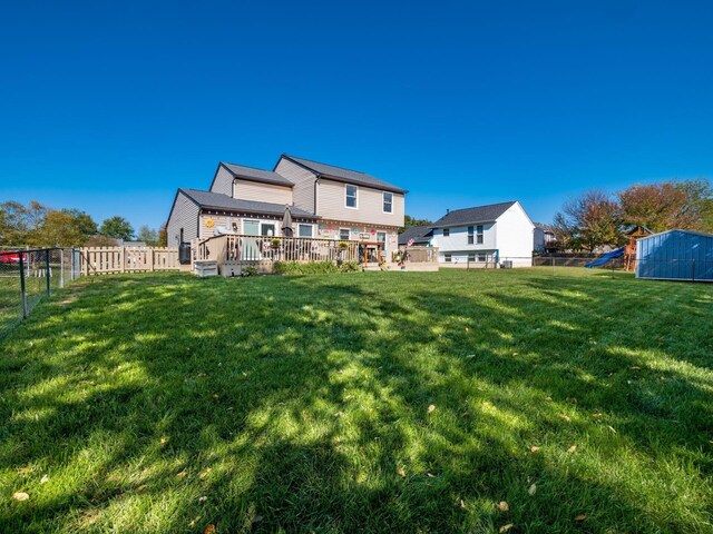 back of house featuring a playground, a deck, and a yard