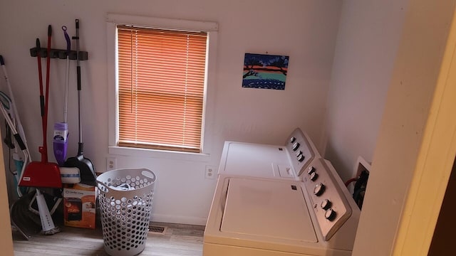 laundry area featuring independent washer and dryer, light hardwood / wood-style floors, and a healthy amount of sunlight