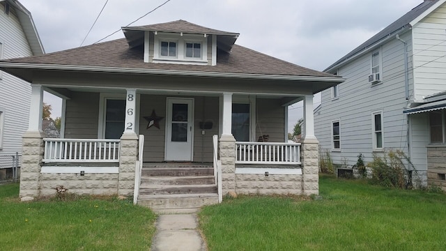 bungalow-style house with cooling unit, covered porch, and a front yard