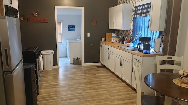 kitchen with wood counters, white refrigerator with ice dispenser, light hardwood / wood-style flooring, washer and dryer, and white cabinetry