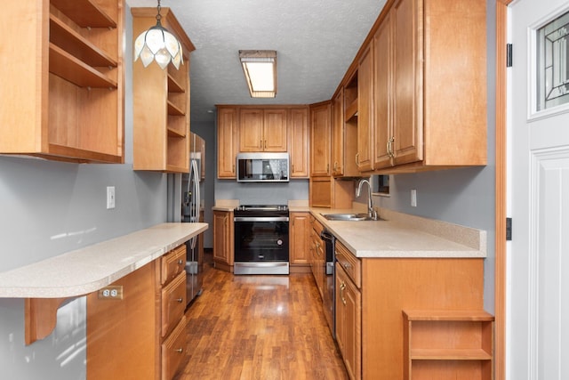 kitchen with sink, hanging light fixtures, dark hardwood / wood-style floors, a textured ceiling, and appliances with stainless steel finishes