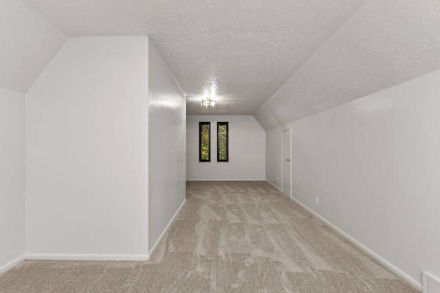 bonus room featuring lofted ceiling, a textured ceiling, and light carpet