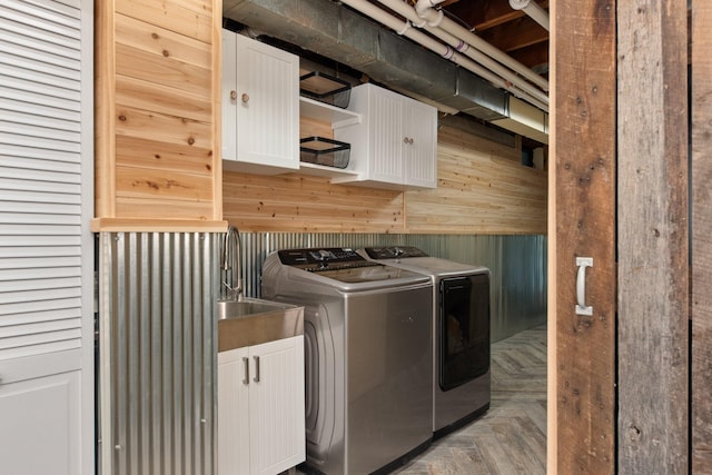 laundry area featuring wood walls, cabinets, parquet floors, sink, and independent washer and dryer