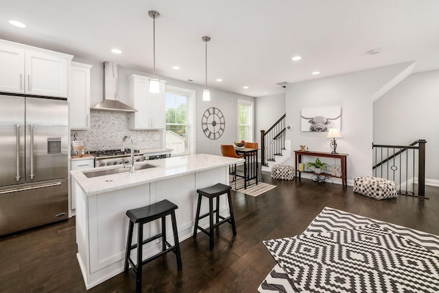 1002 Ewing Aly, Columbus, OH 43201 - kitchen with built in refrigerator, wall chimney exhaust hood, dark wood-type flooring, light stone counters, and white cabinetry