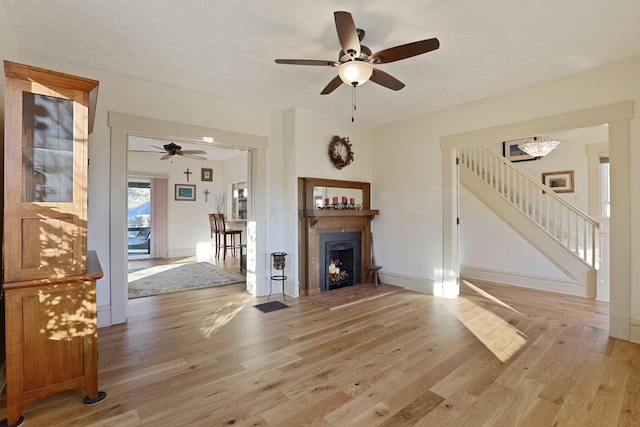 unfurnished living room featuring a textured ceiling, light hardwood / wood-style floors, and ceiling fan