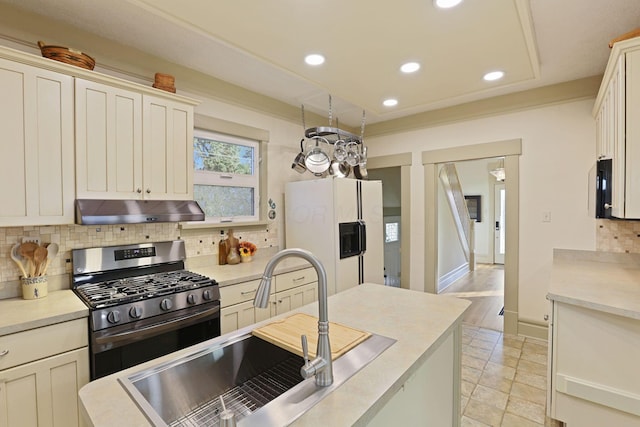 kitchen with white refrigerator with ice dispenser, stainless steel range with gas cooktop, sink, light hardwood / wood-style flooring, and tasteful backsplash