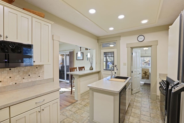 kitchen with decorative backsplash, sink, black appliances, white cabinets, and a center island