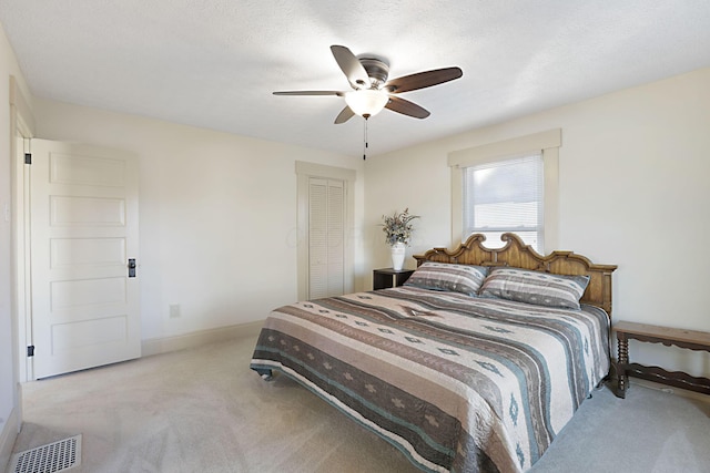 carpeted bedroom with ceiling fan, a textured ceiling, and a closet