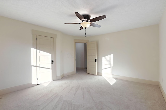 spare room with a textured ceiling, light colored carpet, and ceiling fan