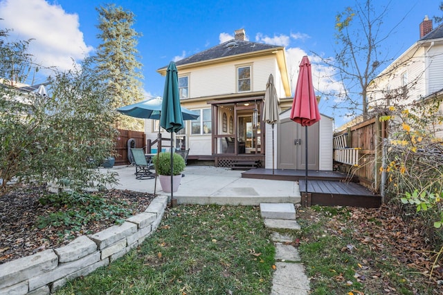 rear view of house with a storage unit, a patio area, and a wooden deck