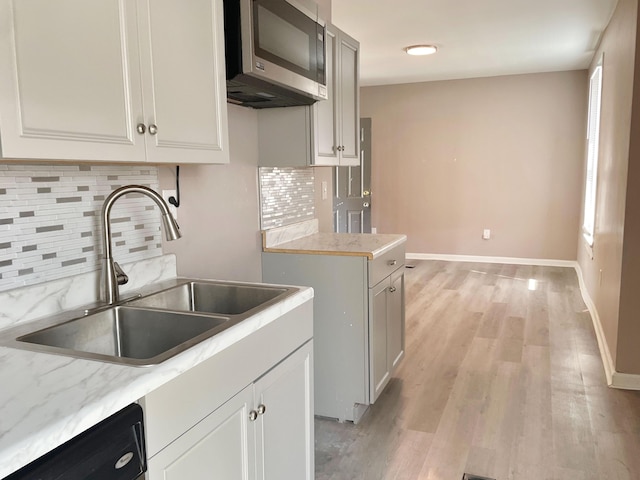 1390 E Livingston Ave, Columbus, OH 43205 - kitchen with stainless steel microwave, dishwashing machine, light wood-style floors, tasteful backsplash, and white cabinetry