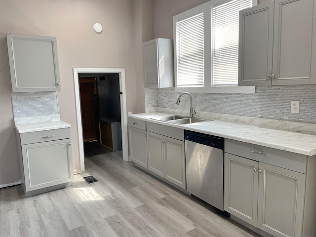 kitchen with tasteful backsplash, gray cabinetry, sink, light hardwood / wood-style flooring, and dishwasher