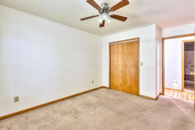 unfurnished bedroom featuring light carpet, a textured ceiling, a closet, and ceiling fan