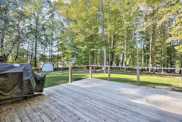 deck featuring grilling area, a yard, and a storage shed