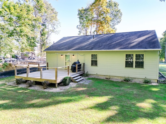 rear view of property featuring a lawn and a deck