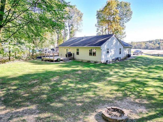 back of property featuring a fire pit, a deck, and a lawn