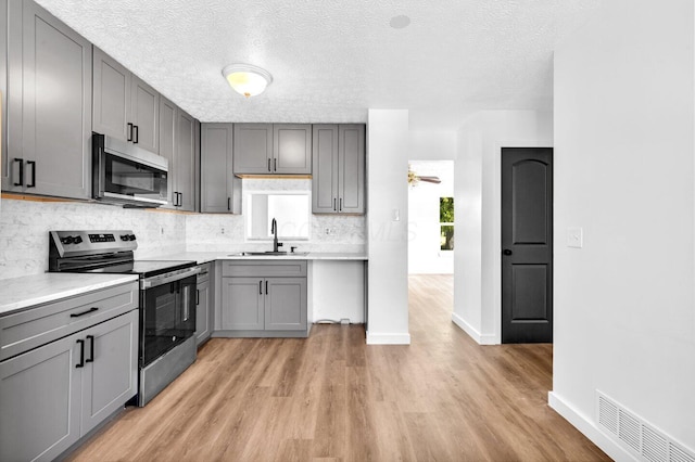 kitchen featuring stainless steel appliances, gray cabinets, light hardwood / wood-style floors, and sink