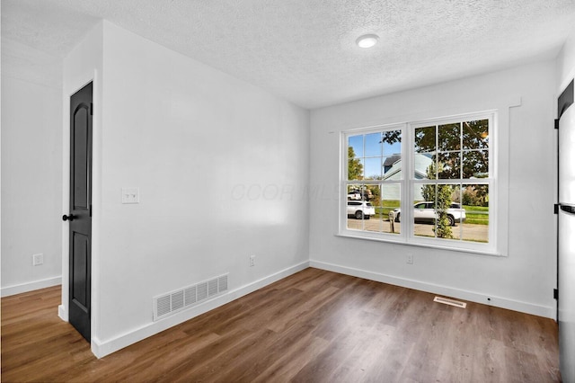 empty room with a textured ceiling and dark wood-type flooring