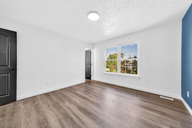 unfurnished room with hardwood / wood-style floors and a textured ceiling