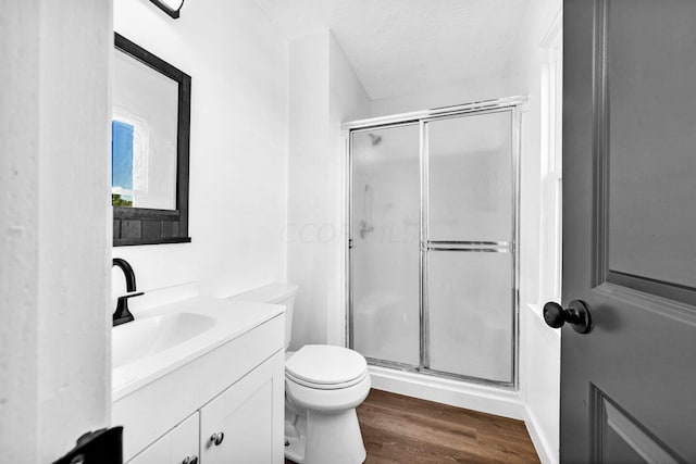 bathroom with a shower with door, vanity, wood-type flooring, and toilet