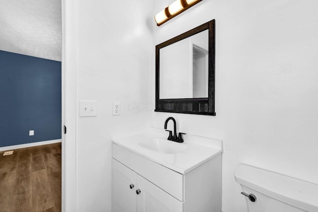 bathroom with hardwood / wood-style flooring, vanity, toilet, and a textured ceiling