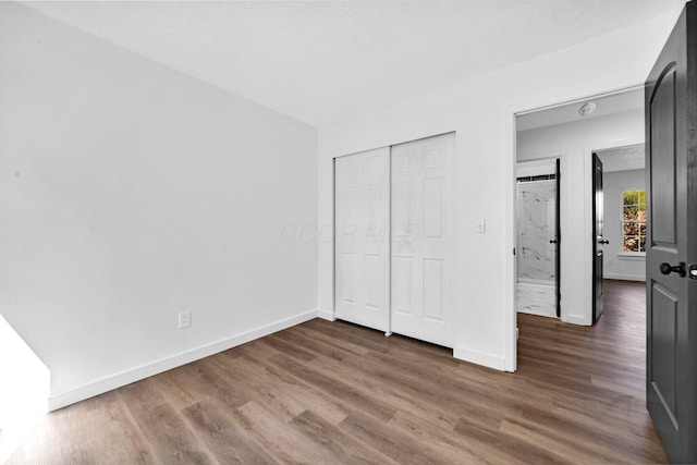 unfurnished bedroom featuring a textured ceiling, a closet, and dark wood-type flooring