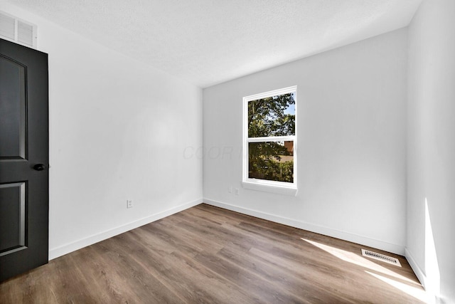 spare room with hardwood / wood-style floors and a textured ceiling