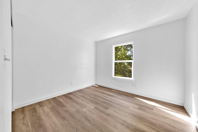 unfurnished room featuring light hardwood / wood-style floors and a textured ceiling