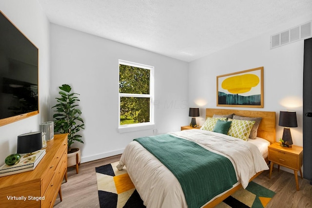 bedroom with wood-type flooring and a textured ceiling