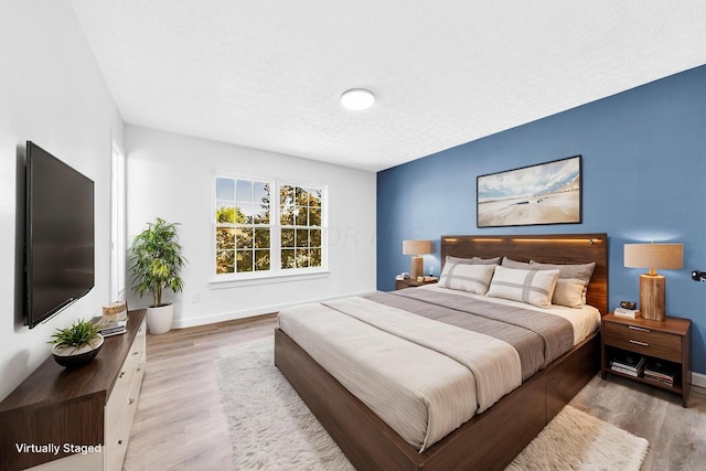 bedroom featuring a textured ceiling and light hardwood / wood-style flooring