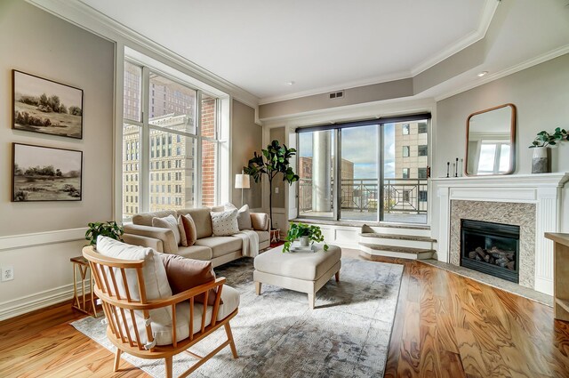 living room featuring a premium fireplace, crown molding, and light hardwood / wood-style floors