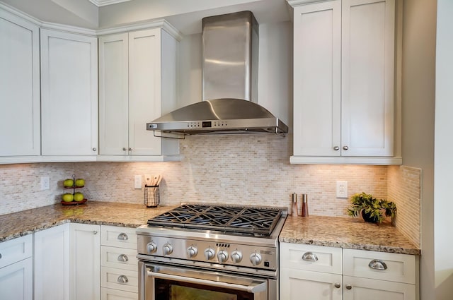 kitchen with stainless steel range, decorative backsplash, white cabinets, and wall chimney exhaust hood