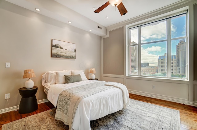 bedroom with hardwood / wood-style flooring, multiple windows, crown molding, and ceiling fan