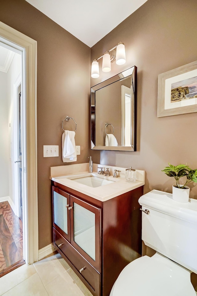 bathroom with tile patterned floors, vanity, toilet, and ornamental molding